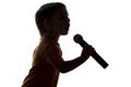Silhouette of little happy boy singing into microphone Royalty Free Stock Photo