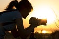 Silhouette portrait of a young woman photographing a beautiful nature at sunset on photo equipment