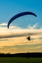 Silhouette of powered paraglider flying during sunset. Vertical shot of paramotor pilot Royalty Free Stock Photo