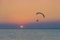Silhouette of powered paraglider soaring flight over the sea against marvellous orange sunset sky. Royalty Free Stock Photo