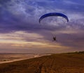 The Silhouette of powered paraglider soaring flight over the sea against sunset sky Royalty Free Stock Photo