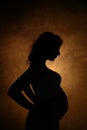 Silhouette of a pregnant girl with a big belly on a gold background Royalty Free Stock Photo