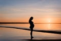 Silhouette of a pregnant woman on beach at sunset. Royalty Free Stock Photo