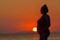 Silhouette of a pregnant woman walking on the beach at sunset Royalty Free Stock Photo