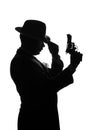 Silhouette of private detective with a gun in right hand. Agent stay side to camera and looks like mafioso Al Capone. Criminal Royalty Free Stock Photo