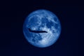 Silhouette of private jet plane flying against huge full moon in dark starry space toned in trendy Classic Blue color of the Year Royalty Free Stock Photo