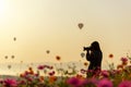 Silhouette professional woman photographer holding camera for take a photo balloon in cosmos meadow nature Royalty Free Stock Photo