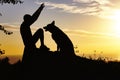 Silhouette profile of happy man and dog sitting in front of each other and playing on nature, boy training German Shepherd at Royalty Free Stock Photo