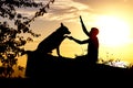 Silhouette profile of hapy man and dog sitting and playing on nature, boy training German Shepherd at sunset in a field, concept Royalty Free Stock Photo