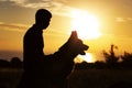 Silhouette profile of a young man with a dog enjoying beautiful sunset in a field, boy fondle his favorite pet on nature, concept Royalty Free Stock Photo