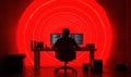 Silhouette of Programmer Working at Desk Surrounded by Red Light Patterns