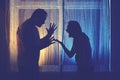 Silhouette of quarreling man and woman at the night window. Married couple husband and wife, violence in evening light of home Royalty Free Stock Photo