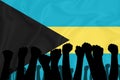 Silhouette of raised arms and clenched fists on the background of the flag of Bahamas. The concept of power, conflict. With place