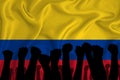 Silhouette of raised arms and clenched fists on the background of the flag of colombia. The concept of power, power, conflict.