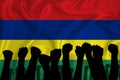 Silhouette of raised arms and clenched fists on the background of the flag of Mauritius. The concept of power, conflict. With