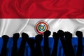 Silhouette of raised arms and clenched fists on the background of the flag of Paraguai. The concept of power, conflict. With