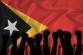 Silhouette of raised arms and clenched fists on the background of the flag of timor. The concept of power, conflict. With place
