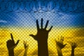 Silhouette of the raised hands of Ukrainian refugees at the border near the barbed wire fence Royalty Free Stock Photo