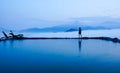 Silhouette rear view of young woman standing near the pool for amazing landscape of blue sky and mountains in morning fog.