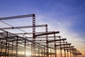 Silhouette of red castellated beam metal structure of large industrial building in construction site against sunset sky background