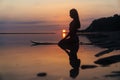 Silhouette and reflection of girl sitting on surfboard at ocean beach on background of beautiful sunset Royalty Free Stock Photo