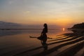 Silhouette and reflection of girl sitting on surfboard at ocean beach on background of beautiful sunset Royalty Free Stock Photo