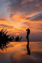 Silhouette and reflection of slim woman on edge infinity luxury pool at sunset Royalty Free Stock Photo