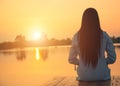 Silhouette of relaxing young woman on wooden pier at the lake in sunset Royalty Free Stock Photo