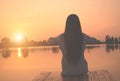 Silhouette of relaxing young woman on wooden pier at the lake in sunset Royalty Free Stock Photo