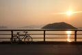 Silhouette of retro bicycle, fence, ocean, mountain at sunset Royalty Free Stock Photo