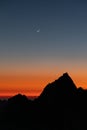 Silhouette of the rocks at sunset with the crescent moon in the sky