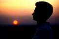 Silhouette of rofile of a young man`s face at sunset in a field