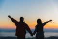 Silhouette of a romantic couple holding hands on top of a mountain at sunrise Royalty Free Stock Photo