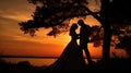 Silhouette of a romantic couple kissing under a tree at sunset with vivid orange sky and tranquil lake in the background Royalty Free Stock Photo