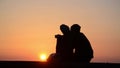 Silhouette of romantic couple in love at sunset at the sea. Boy and girl enjoying at sunset and taking selfie with phones on holid