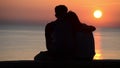 Silhouette of romantic couple in love at sunset at the sea. Boy and girl enjoying at sunset and taking selfie with phones on holid