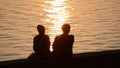 Silhouette of romantic couple in love at sunset at the sea. Boy and girl enjoying at sunset and taking selfie with phones on holid