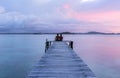 silhouette of romantic couple sitting on old wooden dock at the lake, sunset shot Royalty Free Stock Photo
