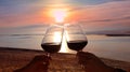 Silhouette romantic couple toasting each other with wine while sitting together on a sandy beach at sunset scene mood