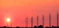 Silhouette row of electric poles with cable lines against orange sunset sky background at countryside, panoramic view Royalty Free Stock Photo