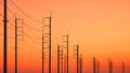 Silhouette rows of electric poles with cable lines against colorful orange sunset sky background, low angle and perspective view Royalty Free Stock Photo