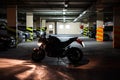 Silhouette of running engine motorcycle standing in the mile of dark underground parking. Light is turning on