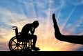 Silhouette of sad disabled woman in wheelchair and hand gesture stop