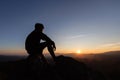 Silhouette of Sad man sitting alone on top of a mountain at sunset, Depression and loneliness.  The concept of stress and gloom Royalty Free Stock Photo