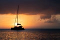 Silhouette of a sail boat sailing off into the of sunset on the distant ocean horizon