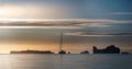 The silhouette of the sailboat and icebergs at sunset.