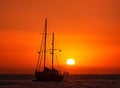 Silhouette of sailing boat with sails down against sun at sunset, sun glare on sea waters. Romantic seascape. Sailboat Royalty Free Stock Photo