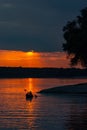 Silhouette of a sailor in a kayak canoe on the lake in the sunset light near an island