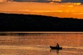 Silhouette of a sailor in a kayak canoe on the lake in the sunset light near an island