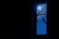 Silhouette of scary man holding gun at door in full moon night Royalty Free Stock Photo